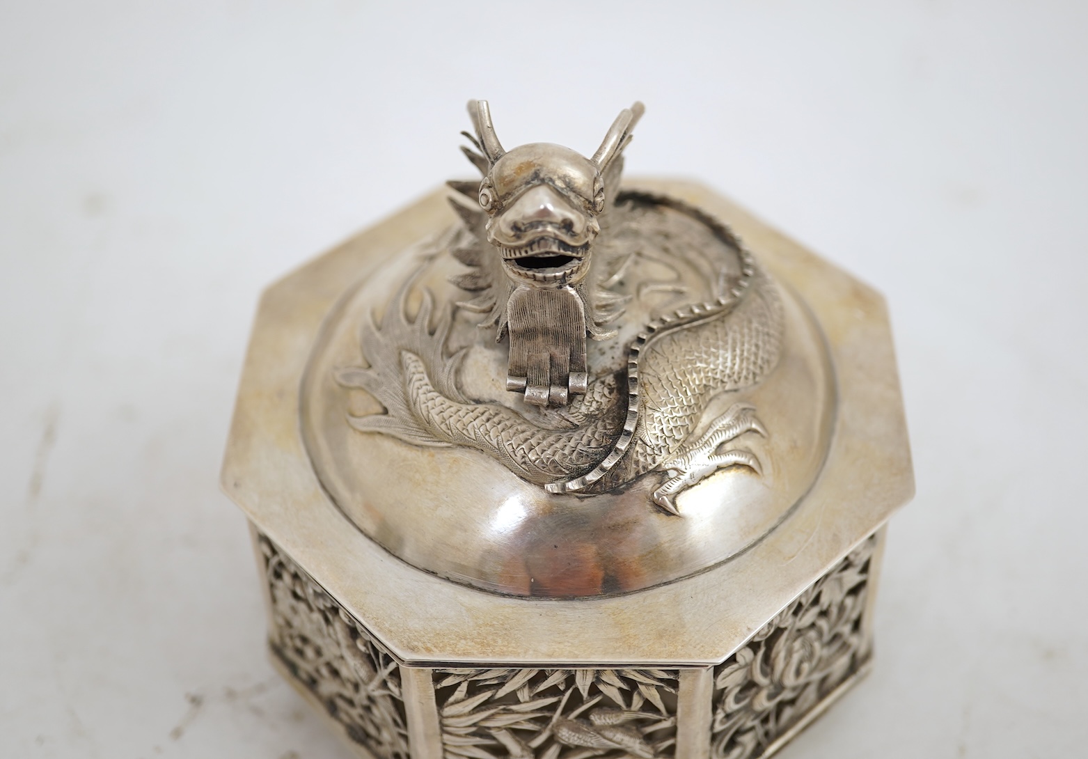 A late 19th century Chinese Export pierced silver card case, maker KMS(Kwong Man Shing), decorated with dragons amid clouds, 10.4cm, together with a Chinese Export pierced silver octagonal box and cover, by Luen Wo?, cir